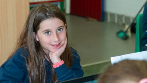 Girl in the classroom setting smiles for the camera